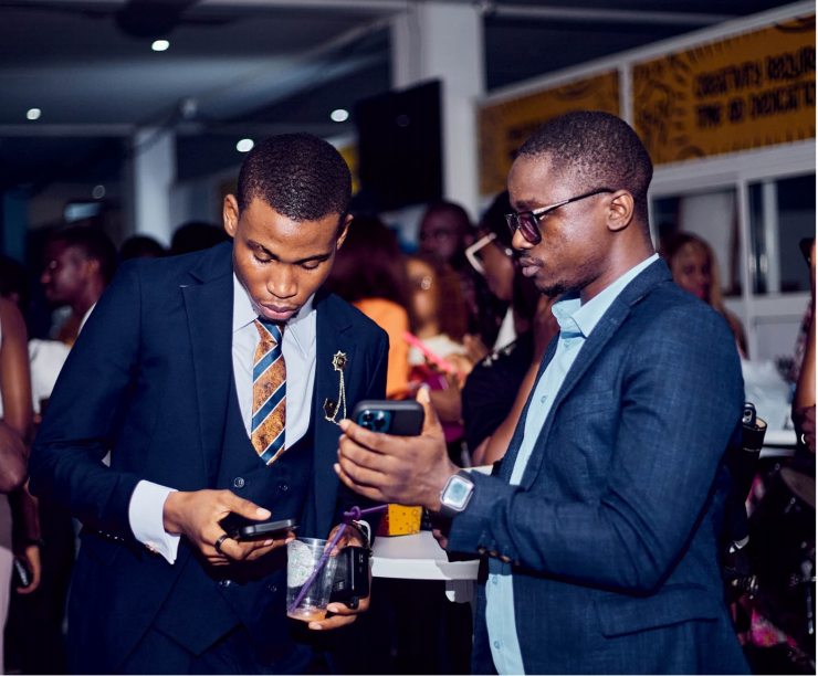 Two young men in suits exchanging contacts at Salone Youth Konnect 2025