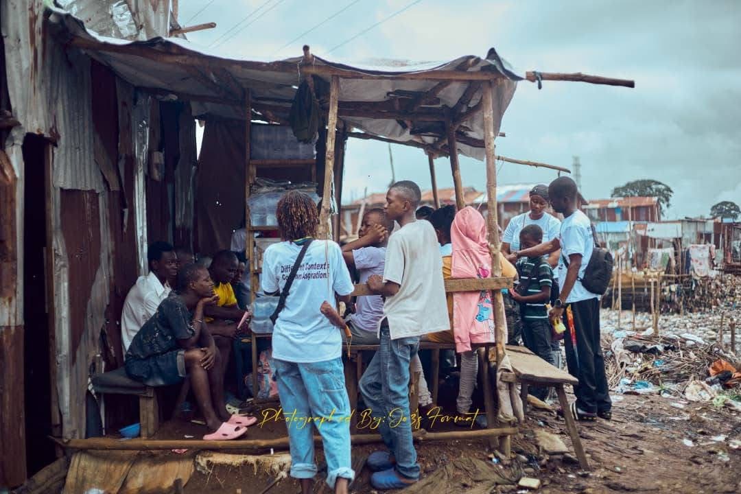 Youth volunteers engaging with children at a community stall during the Kroo Bay outreach