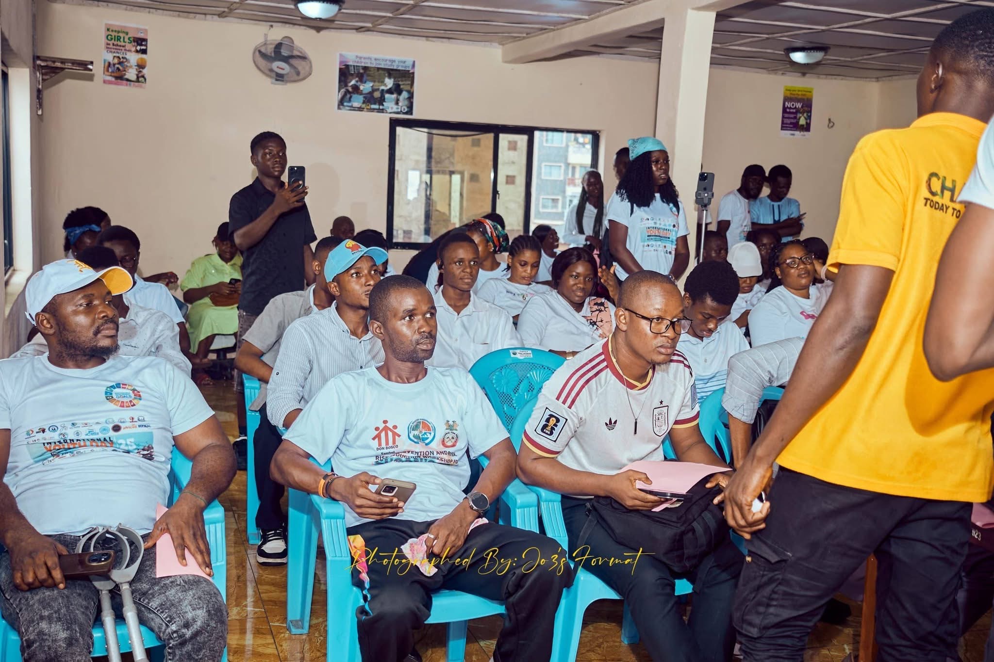 Young participants seated during an International Youth Day session, wearing event t-shirts
