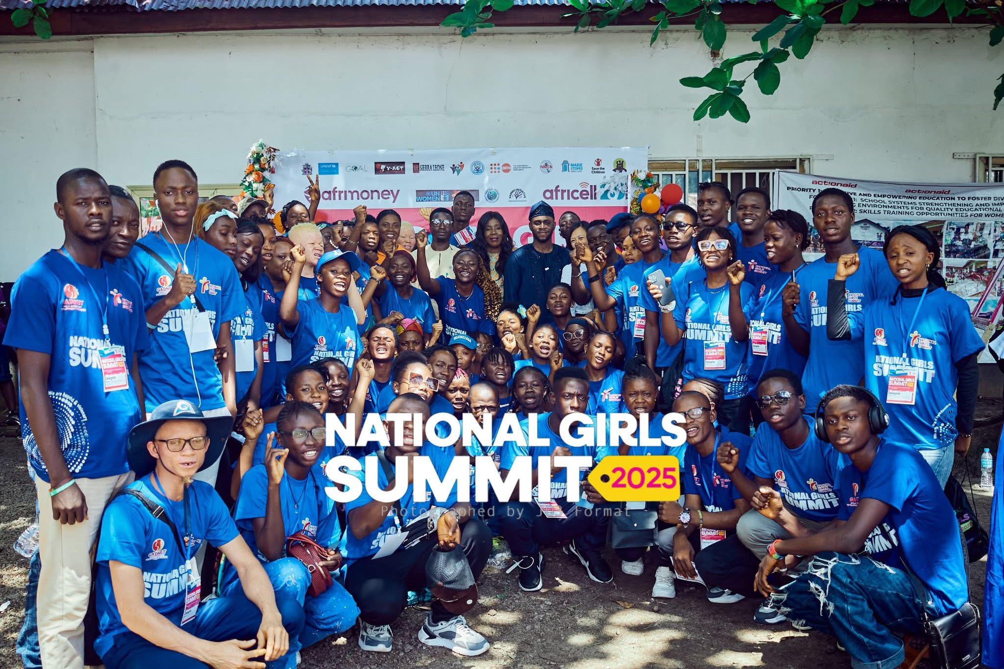 Large group of summit participants in blue National Girls Summit t-shirts posing together in Makeni